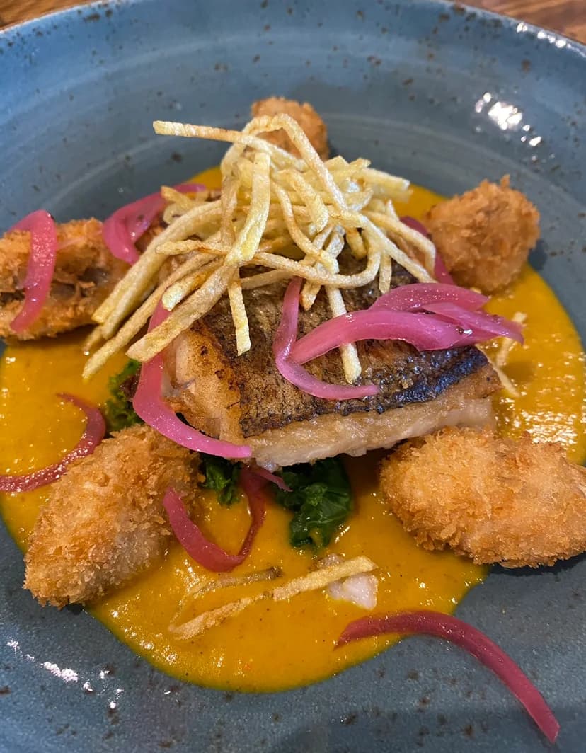 A plated seafood dish with vegetables and crisp garnishes at The Boathouse on Gigha