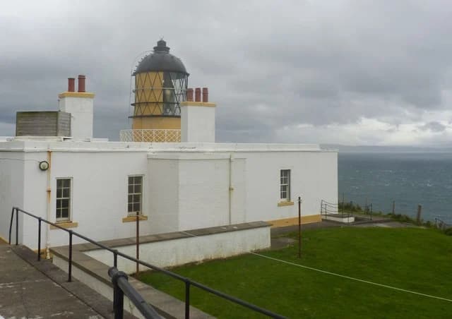 The white Mull of Kintyre Lighthouse and yellow lantern above the sea