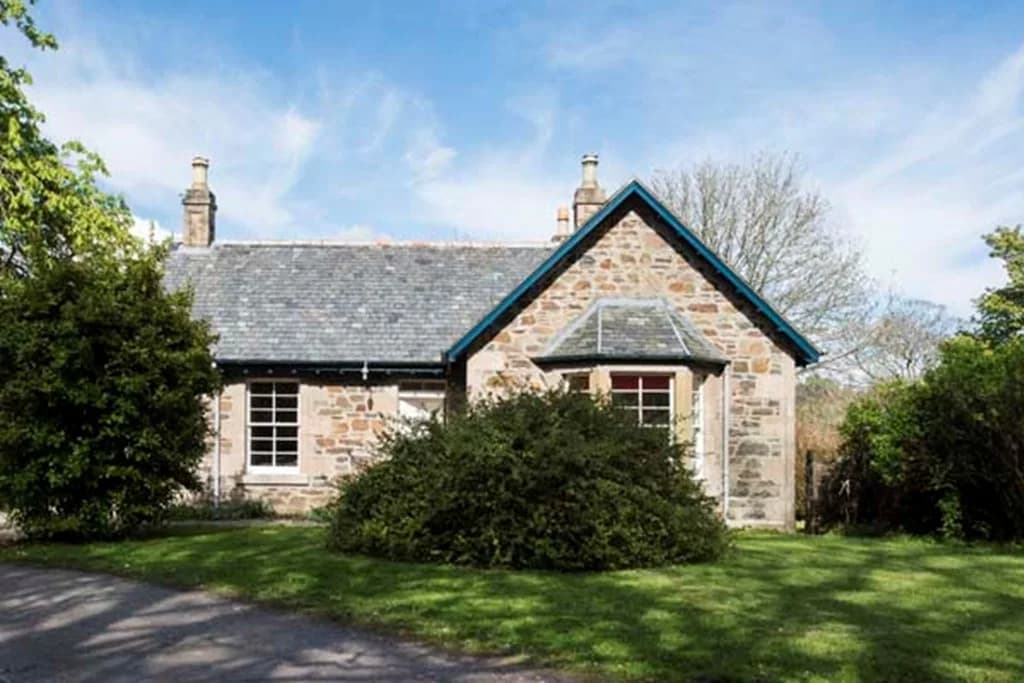 Stone exterior of Saddell Lodge beside its garden and drive