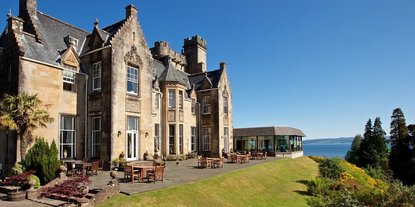 Stonefield Castle Hotel's sunlit stone exterior, terrace and gardens overlooking Loch Fyne