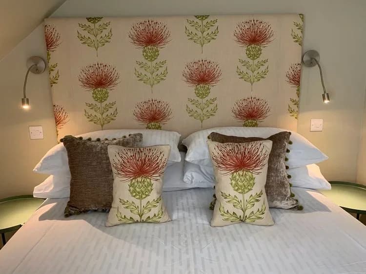 The Hayloft suite's king bed with floral pillows and a matching upholstered headboard at The House at Glenbarr